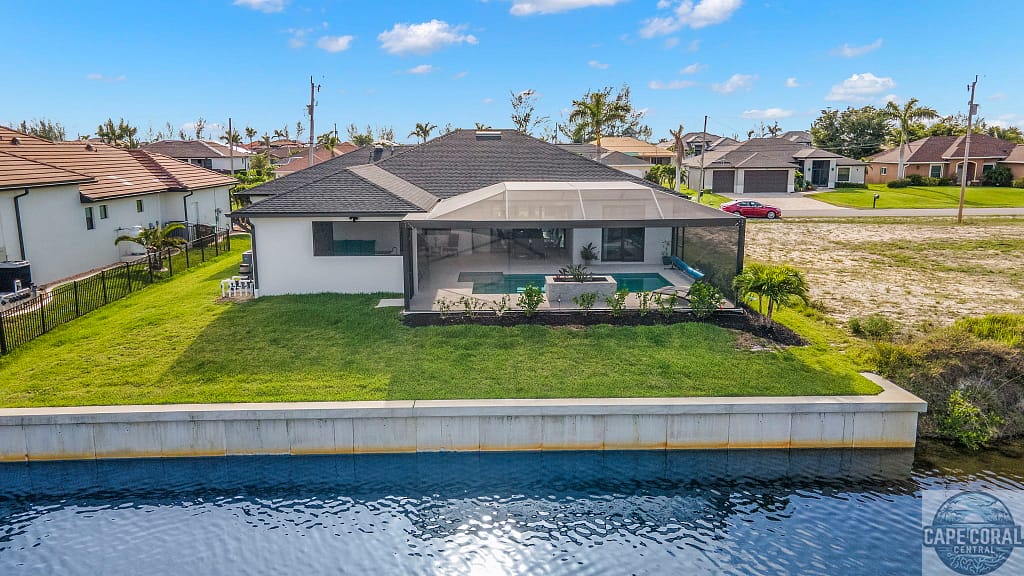 Spacious waterfront home in Cape Coral with green lawn and screened lanai overlooking a canal, with private dock for Gulf access.