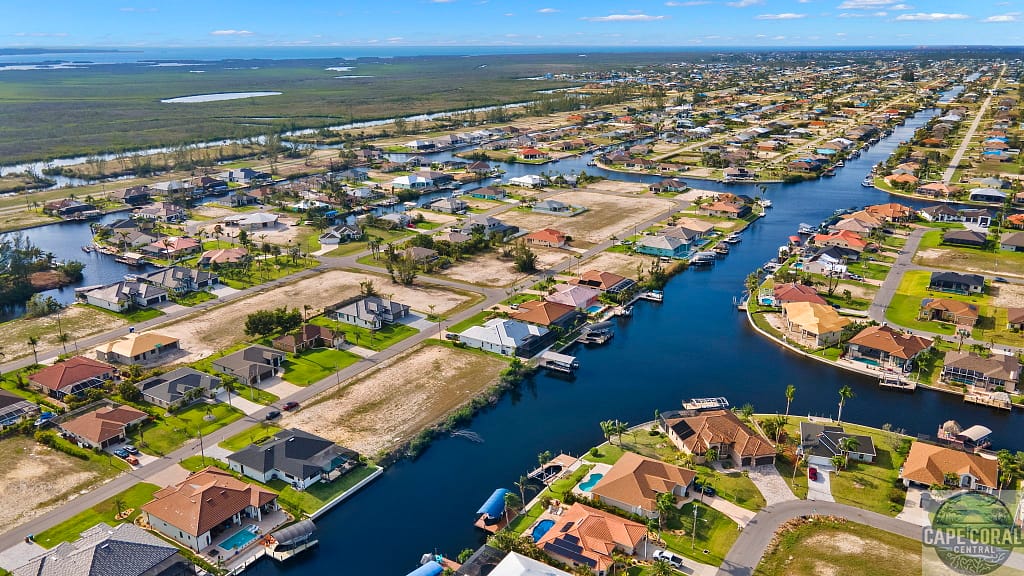 Aerial panorama of Southwest Cape Coral, FL, showing a residential area with homes lining the canals, available lots, and a view extending to the horizon.