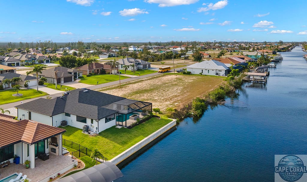 Aerial view of a modern white home with a dark roof and pool on the Spreader Canal in Cape Coral, FL, offering direct Gulf access.