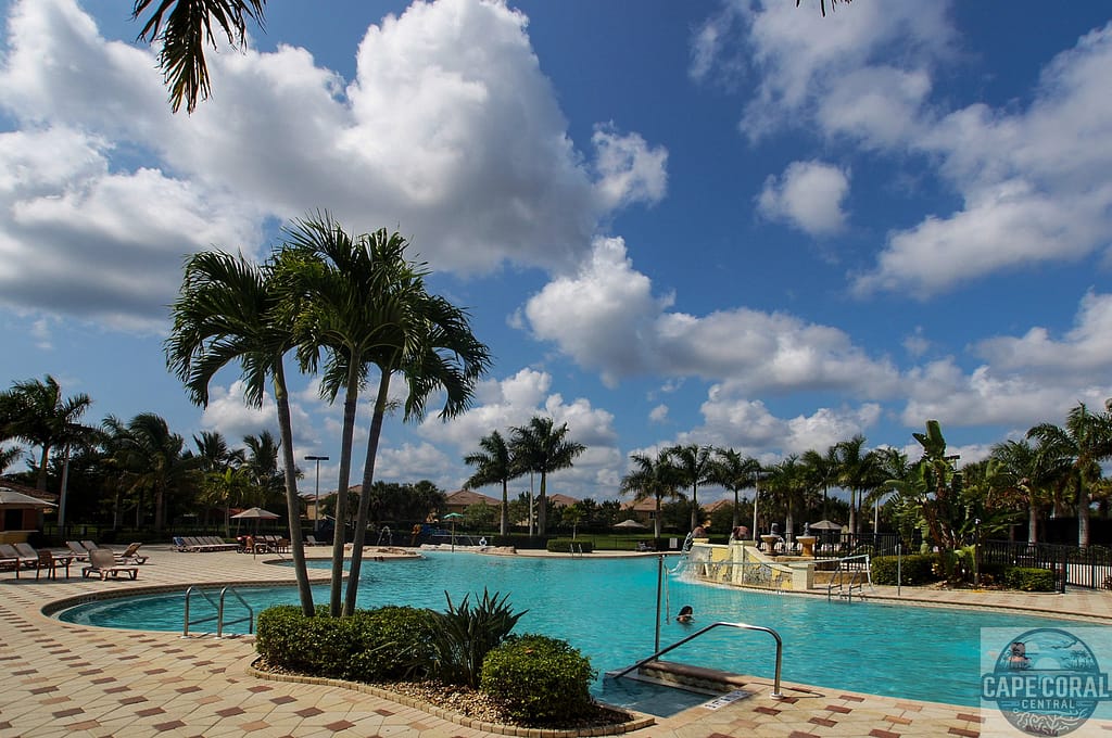 Inviting resort-style pool at Bella Terra surrounded by tropical palm trees and lounge chairs under the beautiful Florida sky, representing the leisurely community lifestyle in Estero.