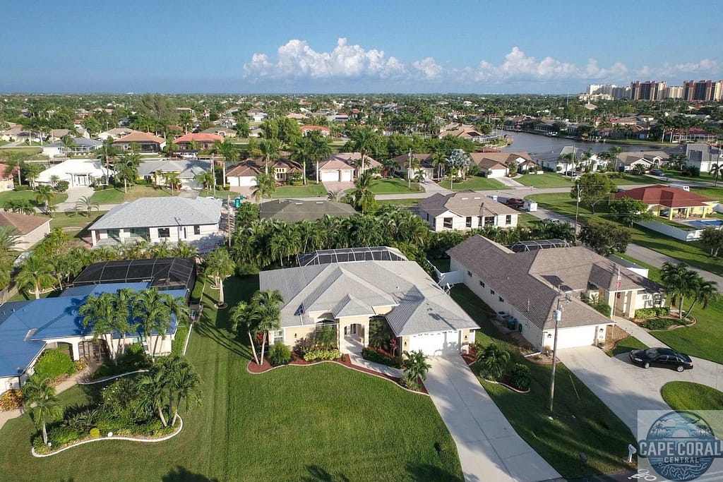 Southwest Cape Coral neighborhood with waterfront homes, manicured lawns, and private docks under a blue sky, illustrating the serene and luxurious lifestyle on offer.
